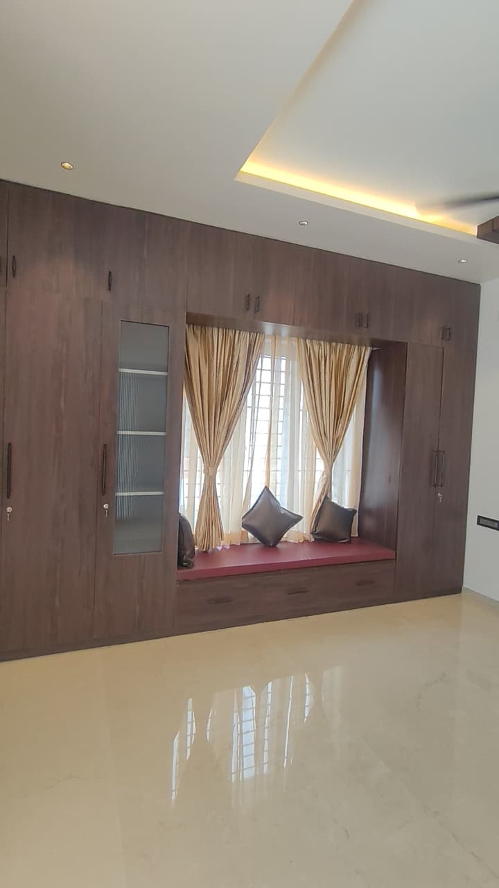 Bedroom built-in wardrobe with glass display and window seat – villa interior design Coimbatore