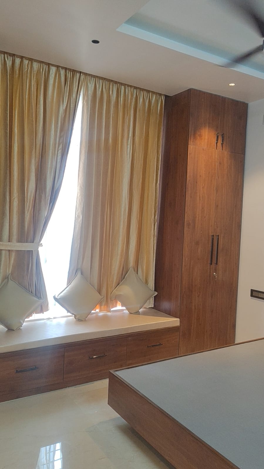 Master bedroom window seat with gold curtains and wood wardrobe – luxury interiors Tamil Nadu