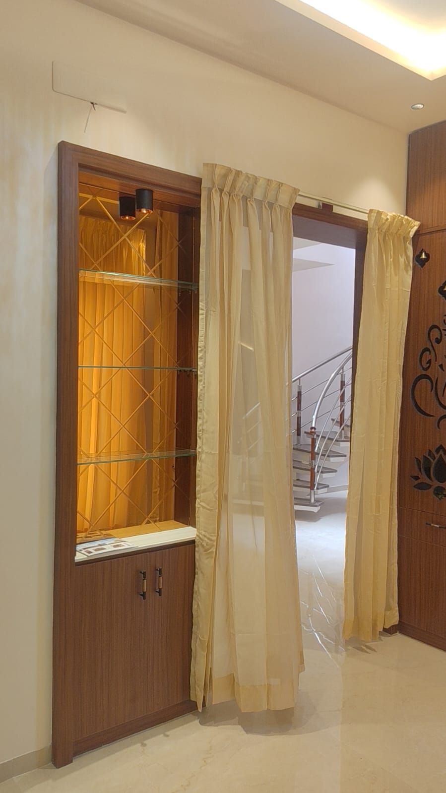 Built-in display cabinet with glass shelves and modern staircase – villa interior Coimbatore