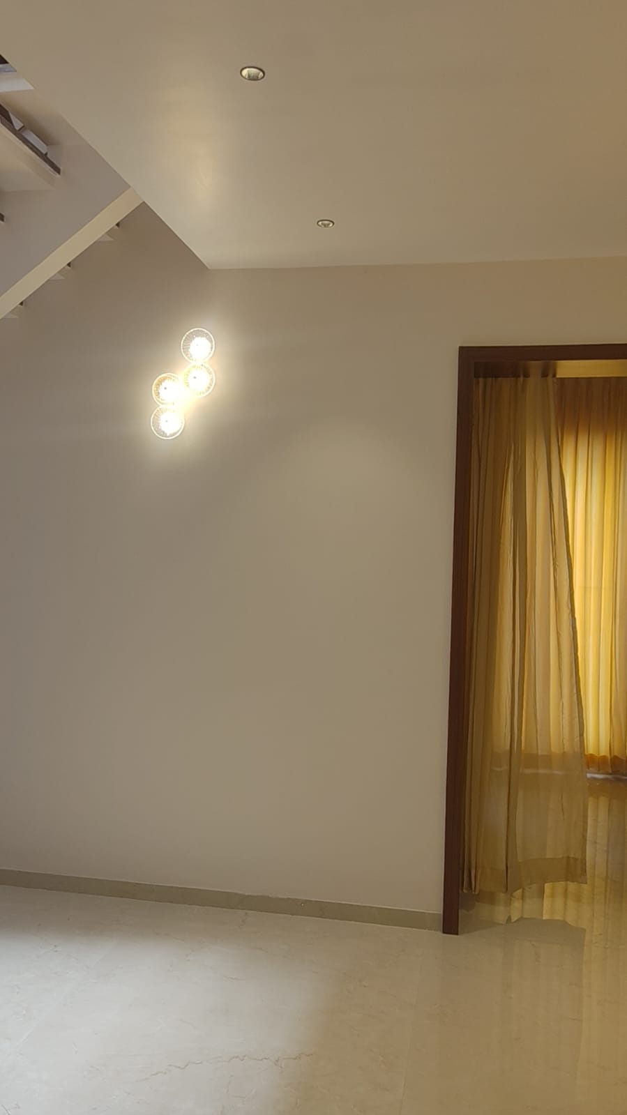 Villa interior lighting detail – designer wall sconce with golden sheer curtains Coimbatore