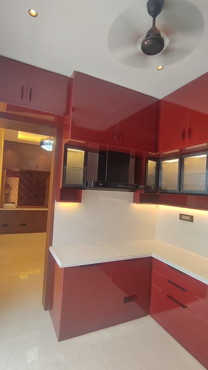 Modular kitchen design Coimbatore – glossy red and white cabinets, chimney and under-cabinet LED lighting
