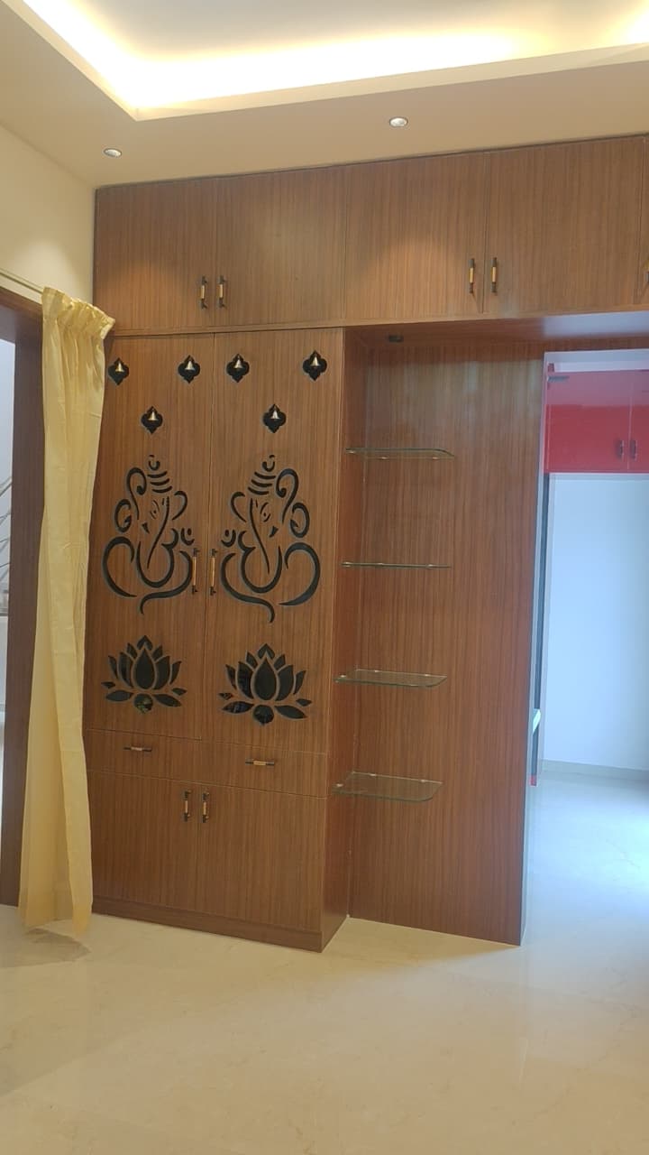 Modern puja unit design Coimbatore – CNC Ganesha motif doors with glass display shelves