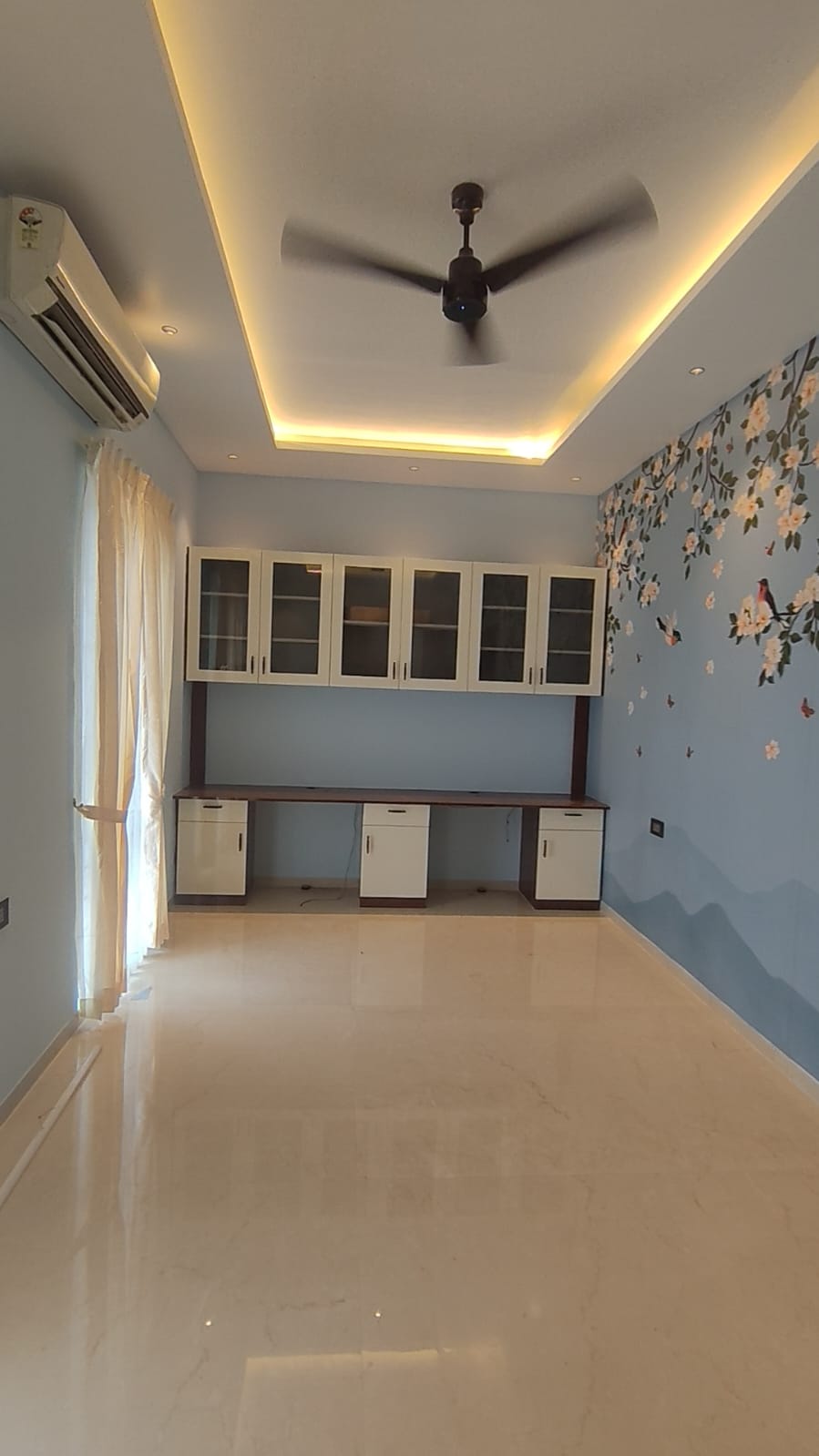 Study room interior design Coimbatore – built-in desk, glass wall cabinets and floral mural